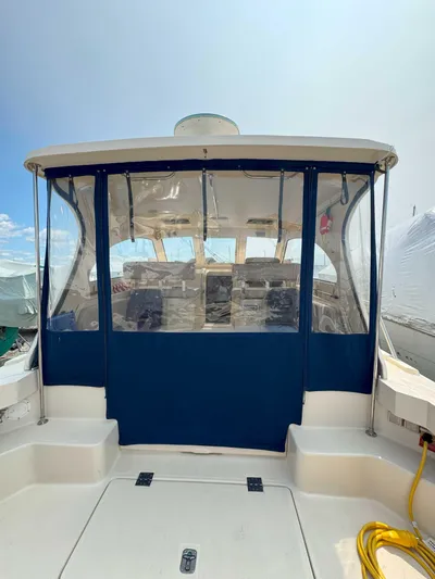 Fetch Yacht Photos Pics 2004 Mainship Pilot 34 boat with blue canopy and clear windows, docked under a bright sky.