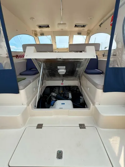 Fetch Yacht Photos Pics 2004 Mainship Pilot 34 interior with engine compartment open, showcasing seating and windows.