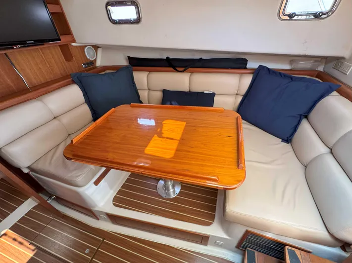 Fetch Yacht Photos Pics 2004 Mainship Pilot 34 interior with wooden table, beige seating, and blue cushions.