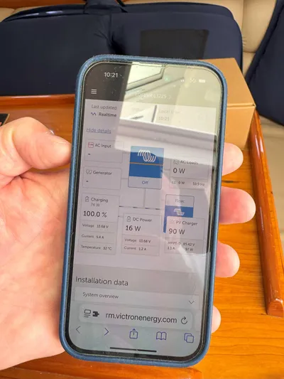 Fetch Yacht Photos Pics Person holding smartphone displaying energy monitoring app on a 2004 Mainship Pilot 34 boat.