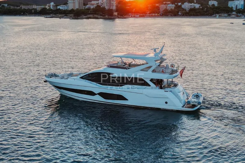 Lady M Yacht Photos Pics 2019 Sunseeker 76 Yacht cruising at sunset near coastal cityscape.