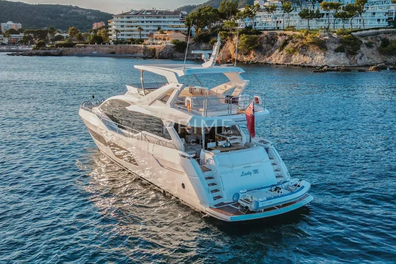 Lady M Yacht Photos Pics 2019 Sunseeker 76 Yacht cruising near scenic coastline at sunset.