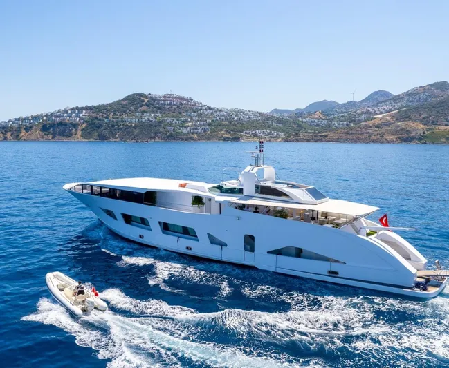  Yacht Photos Pics Luxurious custom yacht cruising in clear blue waters near scenic coastal hills.
