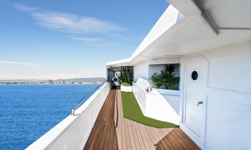  Yacht Photos Pics Luxurious yacht deck with ocean view, featuring wooden flooring and greenery. Custom model 42, 1983.