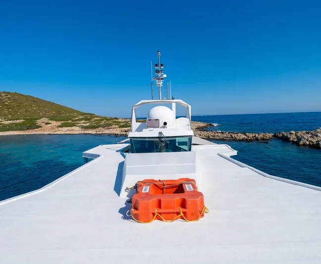  Yacht Photos Pics Custom 42 yacht from 1983 cruising in clear blue waters near rocky coastline.