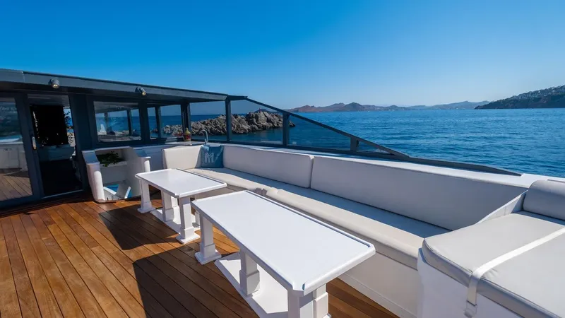  Yacht Photos Pics Luxurious yacht deck with white seating, wooden flooring, and ocean view. Custom model 42, 1983.