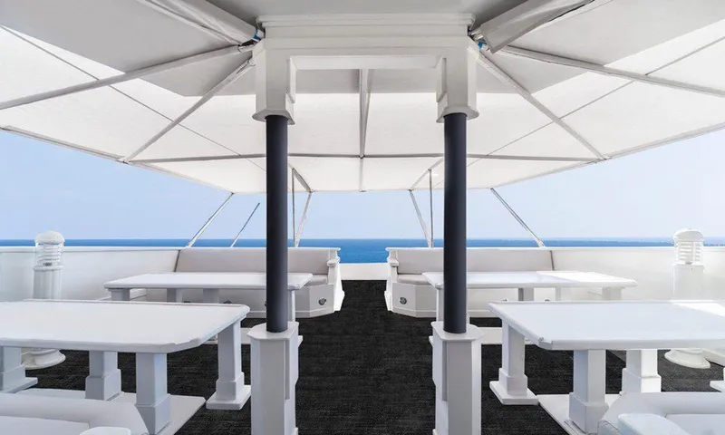  Yacht Photos Pics Spacious yacht deck with white tables, ocean view, and canopy. Custom model 42, 1983.