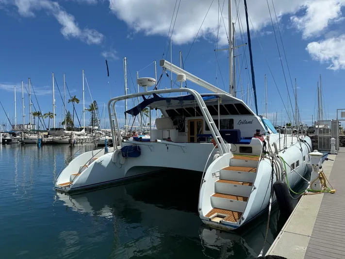 Leilani Yacht Photos Pics Luxury catamaran docked at marina, 2005 Custom model, clear blue sky, calm water.