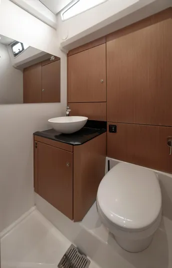  Yacht Photos Pics Luxurious bathroom in 2022 Jeanneau Yacht 60 with modern fixtures and wood cabinetry.