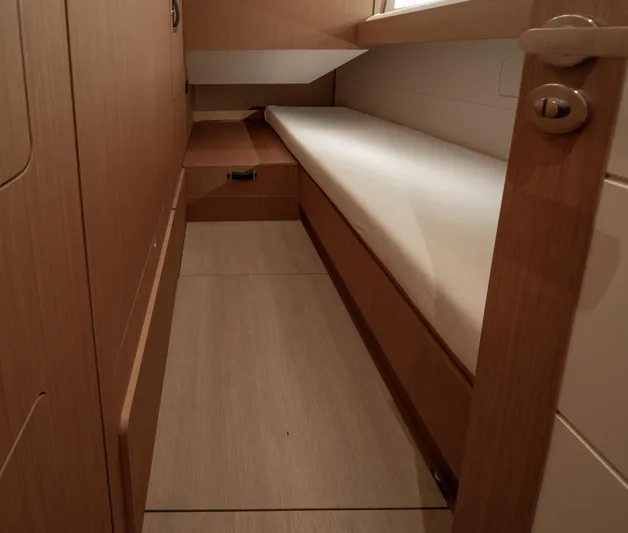  Yacht Photos Pics Interior cabin of 2022 Jeanneau Yacht 60, featuring sleek wooden design and comfortable bedding.