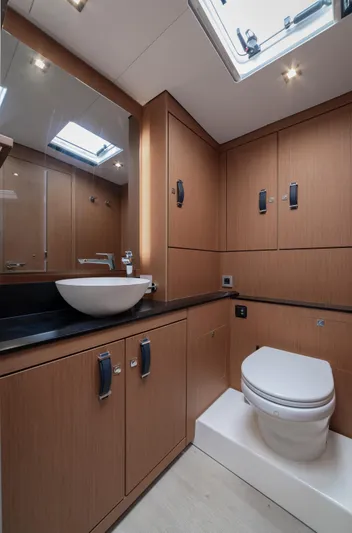  Yacht Photos Pics Luxurious bathroom in 2022 Jeanneau Yacht 60 with modern fixtures and wood cabinetry.