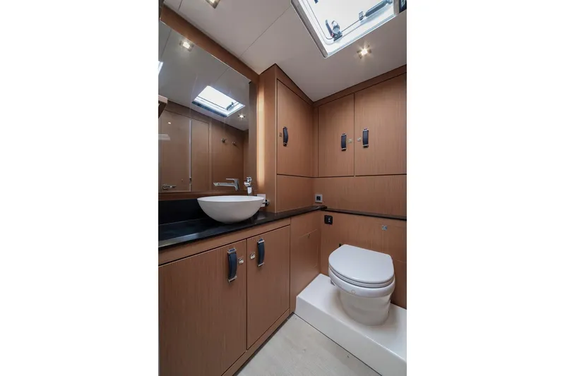  Yacht Photos Pics Luxurious bathroom in 2022 Jeanneau Yacht 60 with modern fixtures and wood cabinetry.