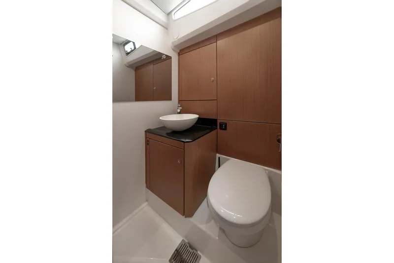  Yacht Photos Pics Modern bathroom in 2022 Jeanneau Yacht 60, featuring sleek wood cabinetry and contemporary fixtures.