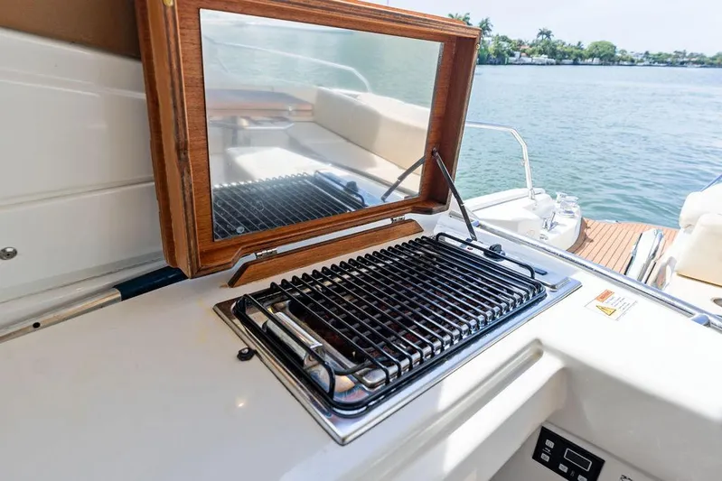 Minion Yacht Photos Pics Outdoor grill on 2014 Cranchi 56 HT yacht, overlooking serene water and lush greenery.
