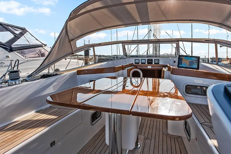  Yacht Photos Pics Luxurious 2022 Hallberg-Rassy 400 yacht cockpit with polished wood table and navigation equipment.
