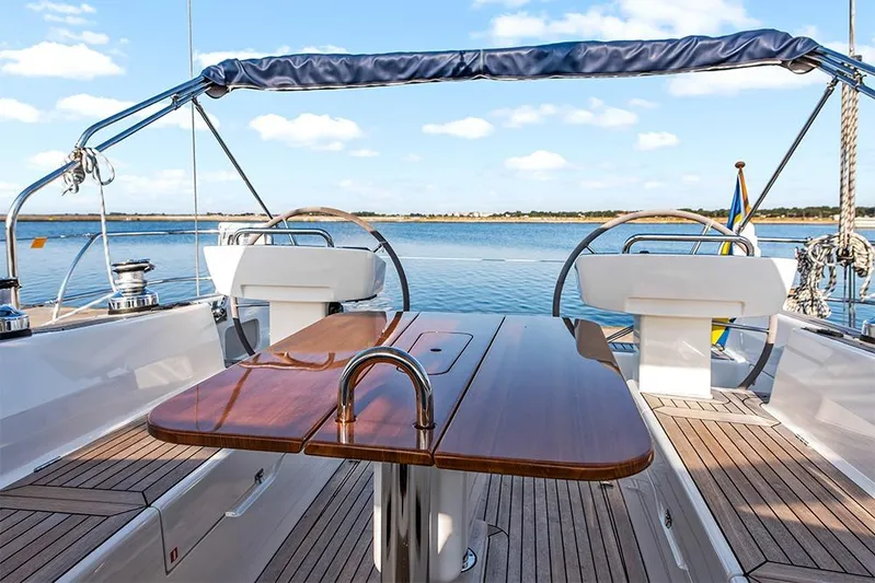  Yacht Photos Pics 2022 Hallberg-Rassy 400 yacht cockpit with wooden table, dual steering wheels, and scenic water view.