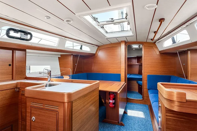  Yacht Photos Pics Interior of 2022 Hallberg-Rassy 400 yacht with wooden finish and blue seating.
