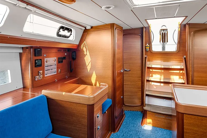 Yacht Photos Pics Interior of 2022 Hallberg-Rassy 400 yacht with wooden finish and blue seating.