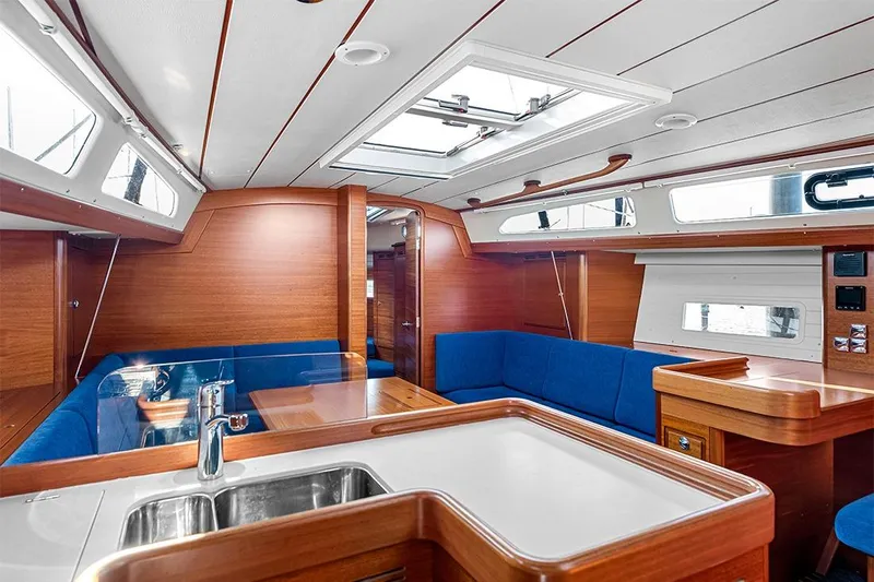  Yacht Photos Pics Interior of 2022 Hallberg-Rassy 400 yacht with blue seating and wooden finishes.
