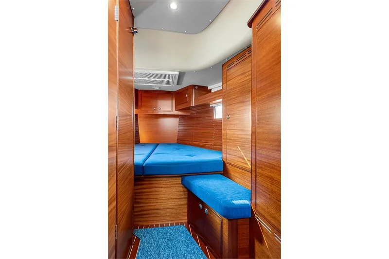  Yacht Photos Pics Luxurious cabin interior of 2022 Hallberg-Rassy 400 yacht with blue cushions and wooden finish.