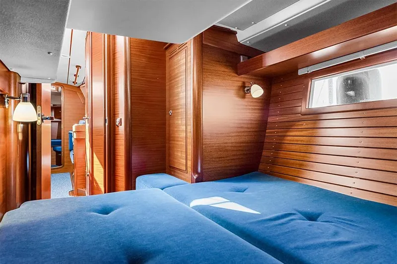  Yacht Photos Pics Interior of 2022 Hallberg-Rassy 400 yacht with wooden paneling and blue upholstery.