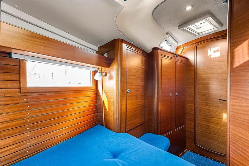  Yacht Photos Pics Luxurious wooden interior of 2022 Hallberg-Rassy 400 yacht cabin with blue seating.
