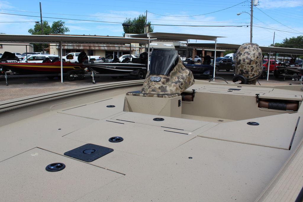 2026 Excel Bolt 183 boat with camouflage seats, parked in a lot with other boats.