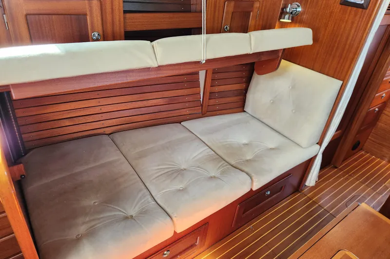 Glendora Yacht Photos Pics Interior of a 2007 Hallberg-Rassy 37 yacht with cushioned seating and wooden paneling.