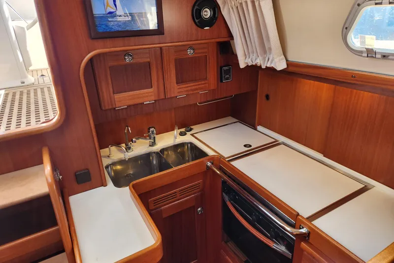 Glendora Yacht Photos Pics 2007 Hallberg-Rassy 37 yacht interior kitchen with wooden cabinets and stainless steel sink.