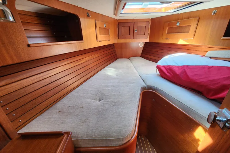 Glendora Yacht Photos Pics Cozy cabin interior of 2007 Hallberg-Rassy 37 sailboat with wooden finish and bedding.