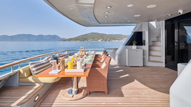 Kintaro Yacht Photos Pics Luxurious 2005 Cantieri di Pisa Akhir 38 yacht deck with dining area and scenic ocean view.