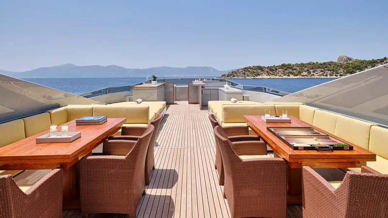 Kintaro Yacht Photos Pics Luxury yacht deck with seating, tables, and ocean view; Cantieri di Pisa Akhir 38, 2005 model.