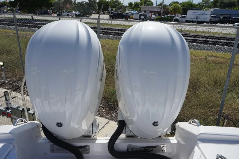  Yacht Photos Pics Twin outboard engines on a 2025 Sea Fox 282 Hybrid LT boat, parked near a fence.
