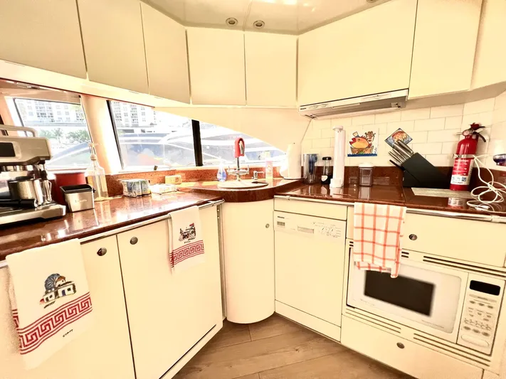 Por Fin Yacht Photos Pics Modern kitchen on a 1999 Fairline Squadron 65 yacht with white cabinets and appliances.