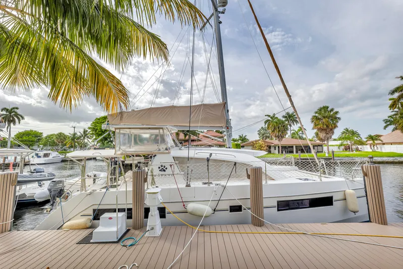  Yacht Photos Pics 2017 Leopard 40 catamaran docked by palm trees, under a cloudy sky.