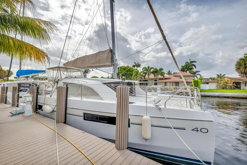  Yacht Photos Pics 2017 Leopard 40 catamaran docked by palm trees, under a cloudy sky.