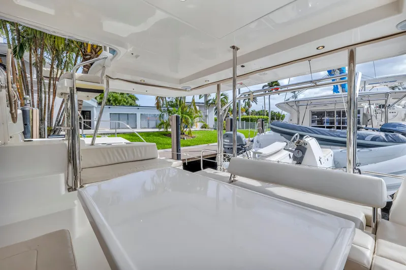  Yacht Photos Pics Spacious deck of 2017 Leopard 40 yacht with seating and table, docked near palm trees.