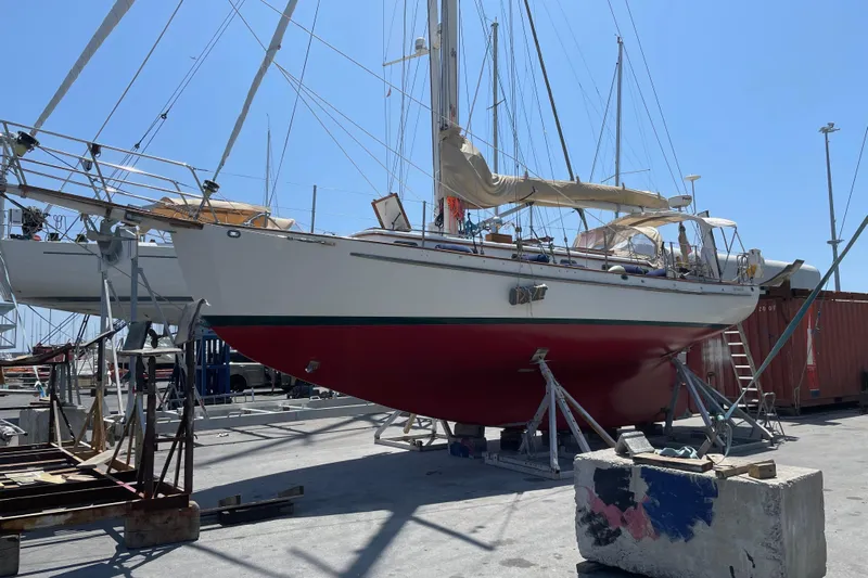 Begonia Yacht Photos Pics Custom 1988 Atkin & Lange Cutter sailboat on dry dock, red hull, marina background.