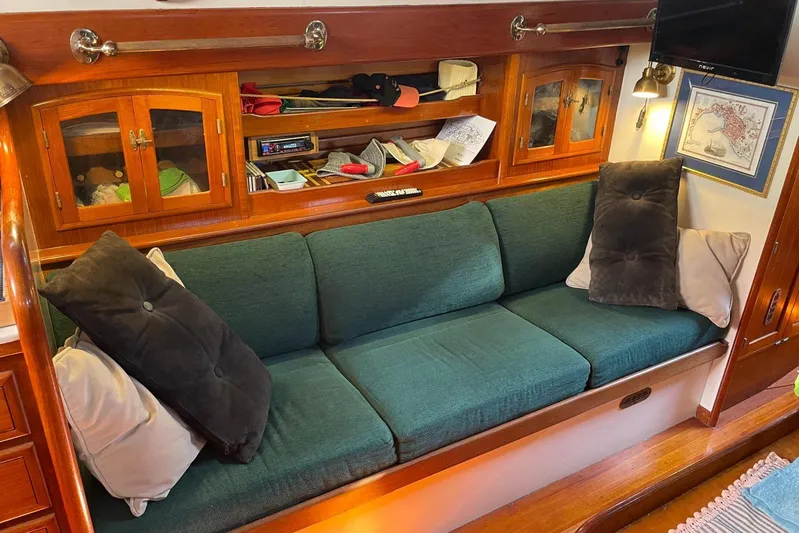 Begonia Yacht Photos Pics Cozy cabin interior of 1988 Custom Atkin & Lange Cutter with green sofa and wooden cabinets.