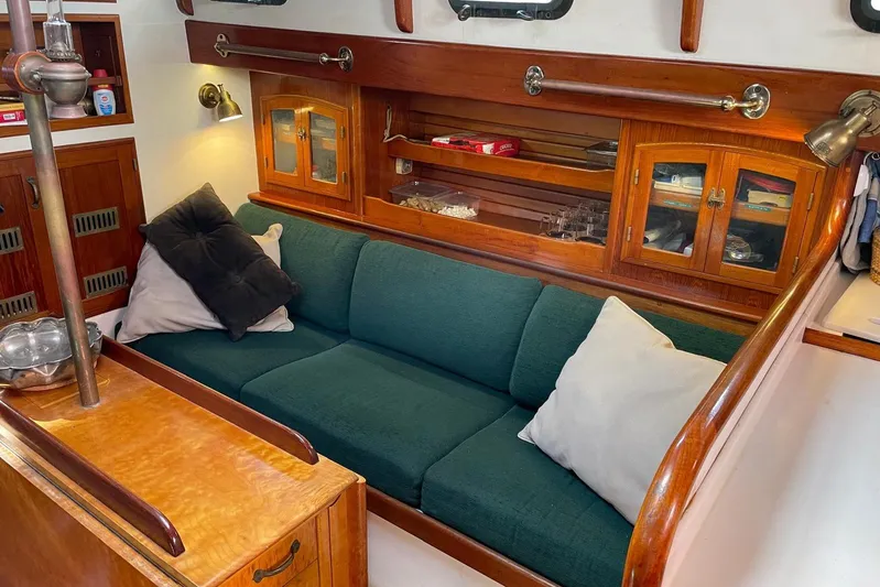 Begonia Yacht Photos Pics Cozy cabin interior of 1988 Custom Atkin & Lange Cutter with green sofa and wooden cabinetry.