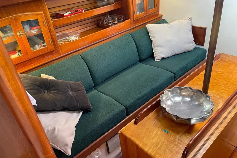 Begonia Yacht Photos Pics Cozy cabin interior of 1988 Atkin & Lange Cutter with green sofa and wooden cabinetry.