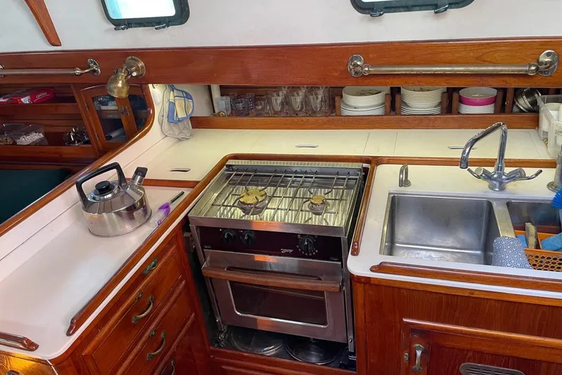Begonia Yacht Photos Pics Cozy boat kitchen with stove, sink, and wooden cabinets on 1988 Atkin & Lange Cutter.