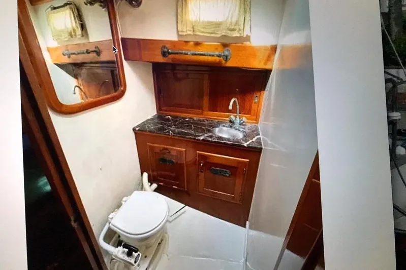 Begonia Yacht Photos Pics Compact boat bathroom with wooden cabinetry, marble countertop, and mirror, featuring a toilet and sink.