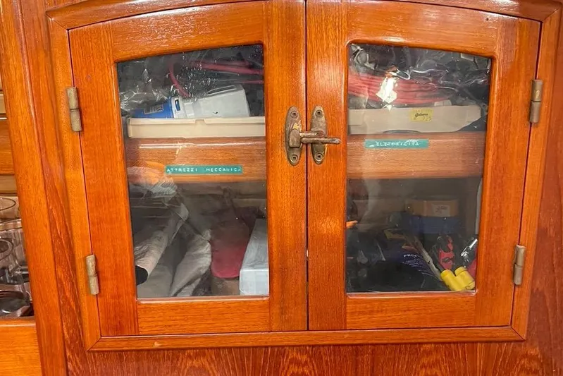 Begonia Yacht Photos Pics Wooden cabinet with glass doors, displaying tools and labeled compartments, aboard a 1988 Atkin & Lange Cutter.