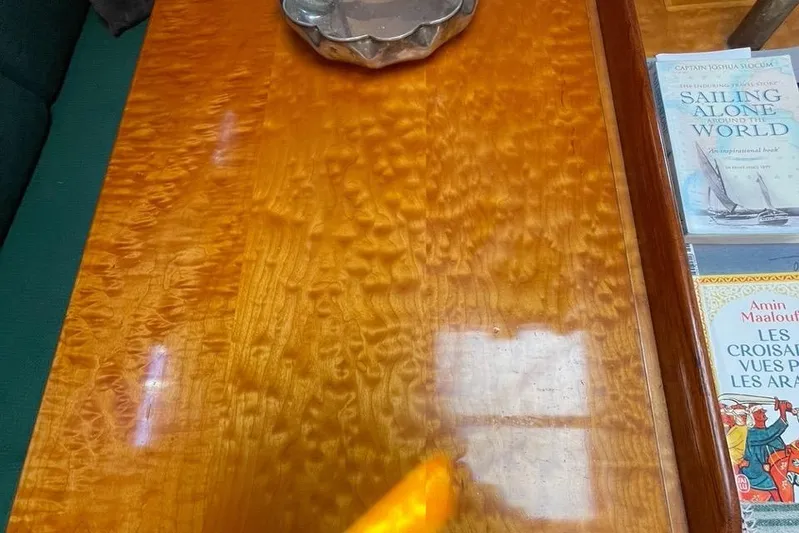 Begonia Yacht Photos Pics Polished wooden table with books, including "Sailing Alone Around the World," on a Custom Atkin & Lange Cutter.