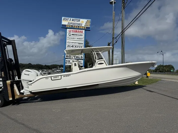 Yacht Photos Pics 2025 Key West 291 FS boat on forklift at dealership, clear sky background.
