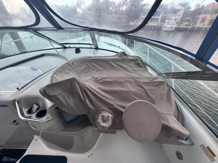 Los Sue&Ntilde;os Yacht Photos Pics 1999 Sea Ray 400 Sundancer helm with covered controls, docked by waterfront homes.