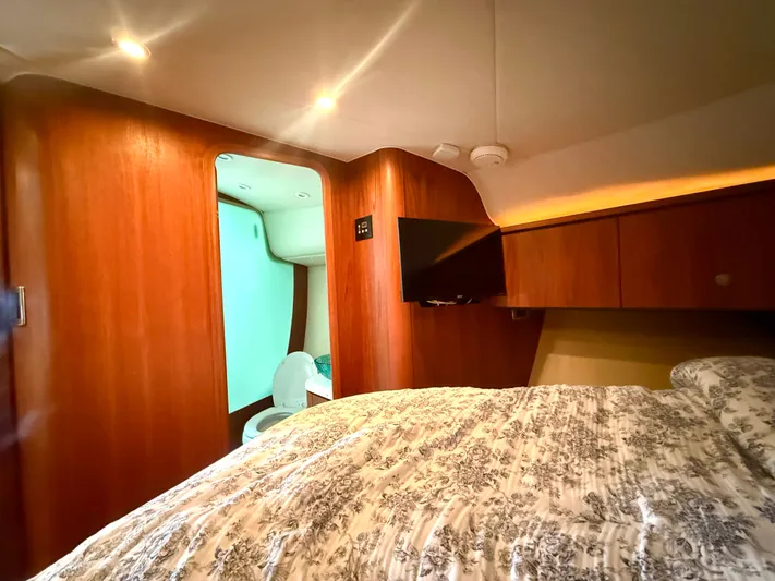 Relentless Yacht Photos Pics 2006 Tiara Yachts 4300 Sovran interior with bed, TV, and wooden cabinetry.