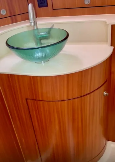  Yacht Photos Pics 2017 Pursuit OS 385 Offshore bathroom with glass vessel sink and wooden cabinetry.