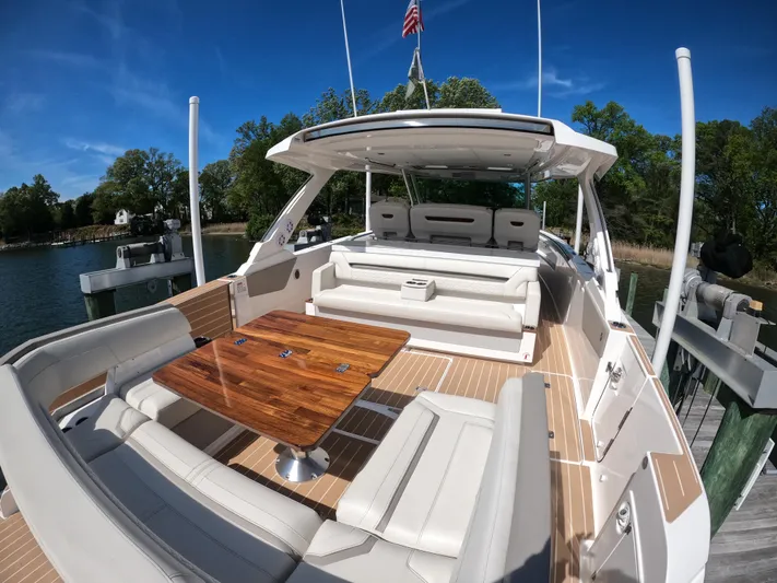  Yacht Photos Pics 2024 Tiara Yachts 43 LS with elegant seating and wooden table, docked by a serene waterfront.